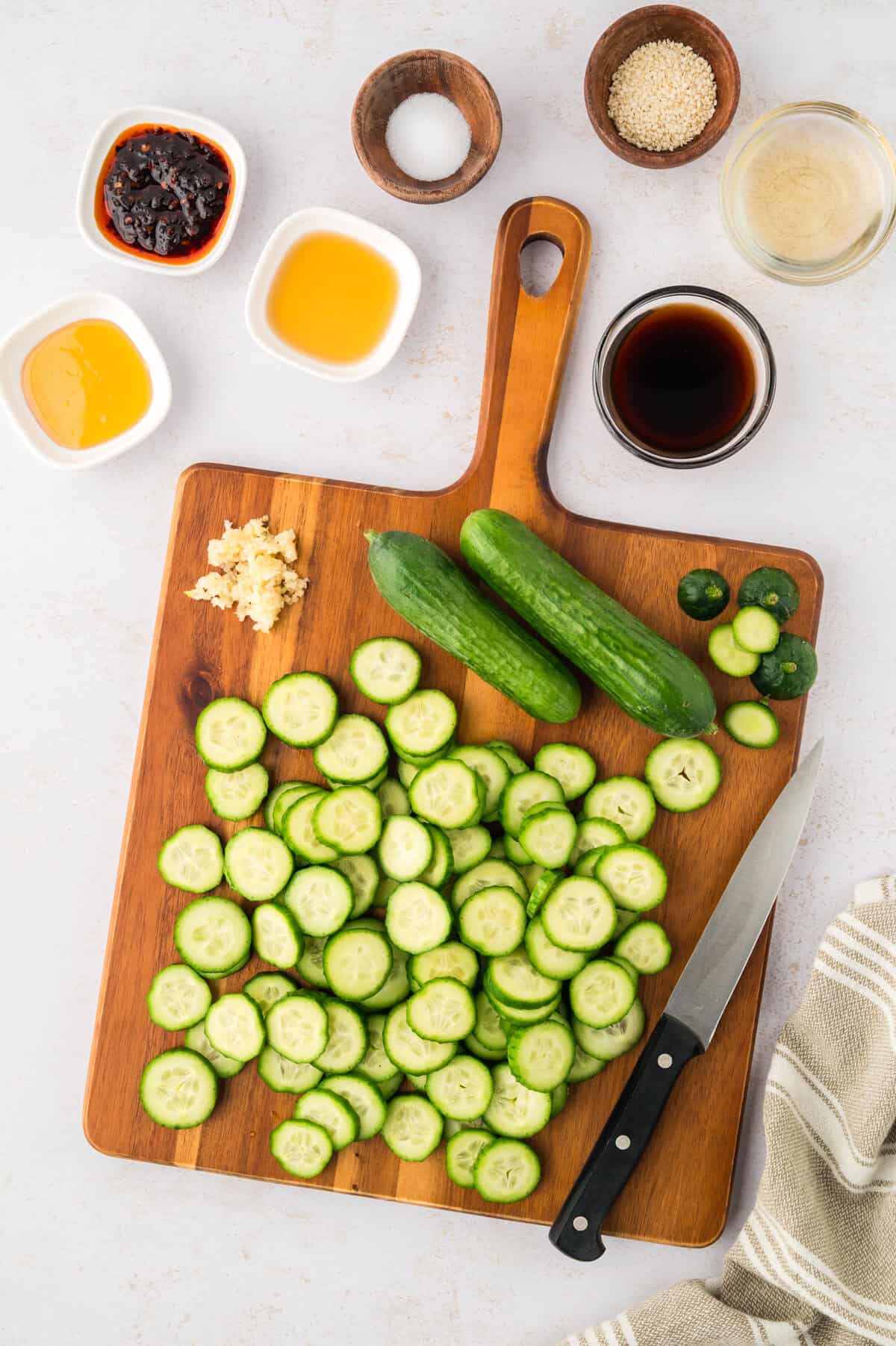 Sliced cucumbers on cutting board.
