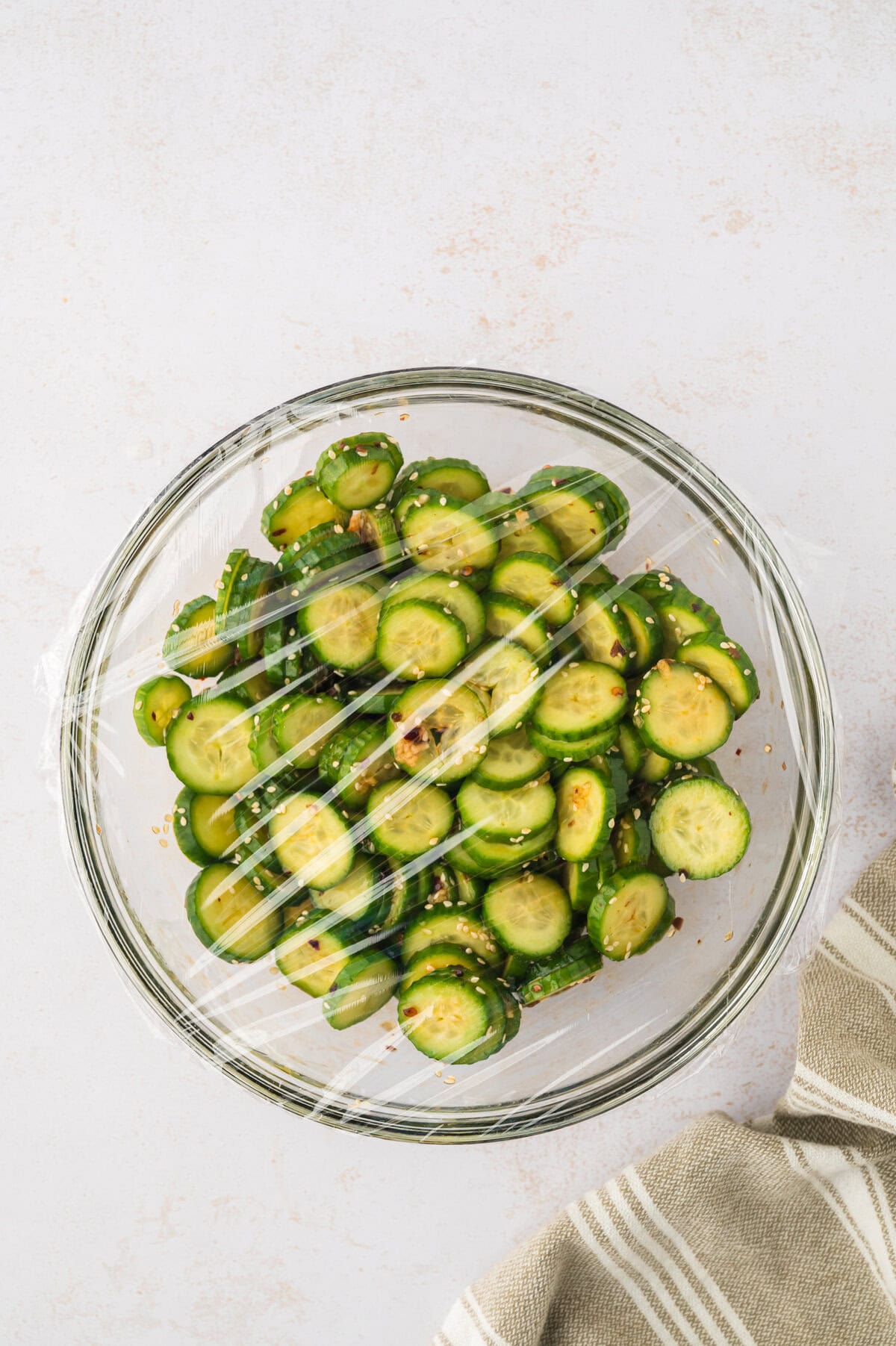 Plastic wrap covering cucumber salad recipe.