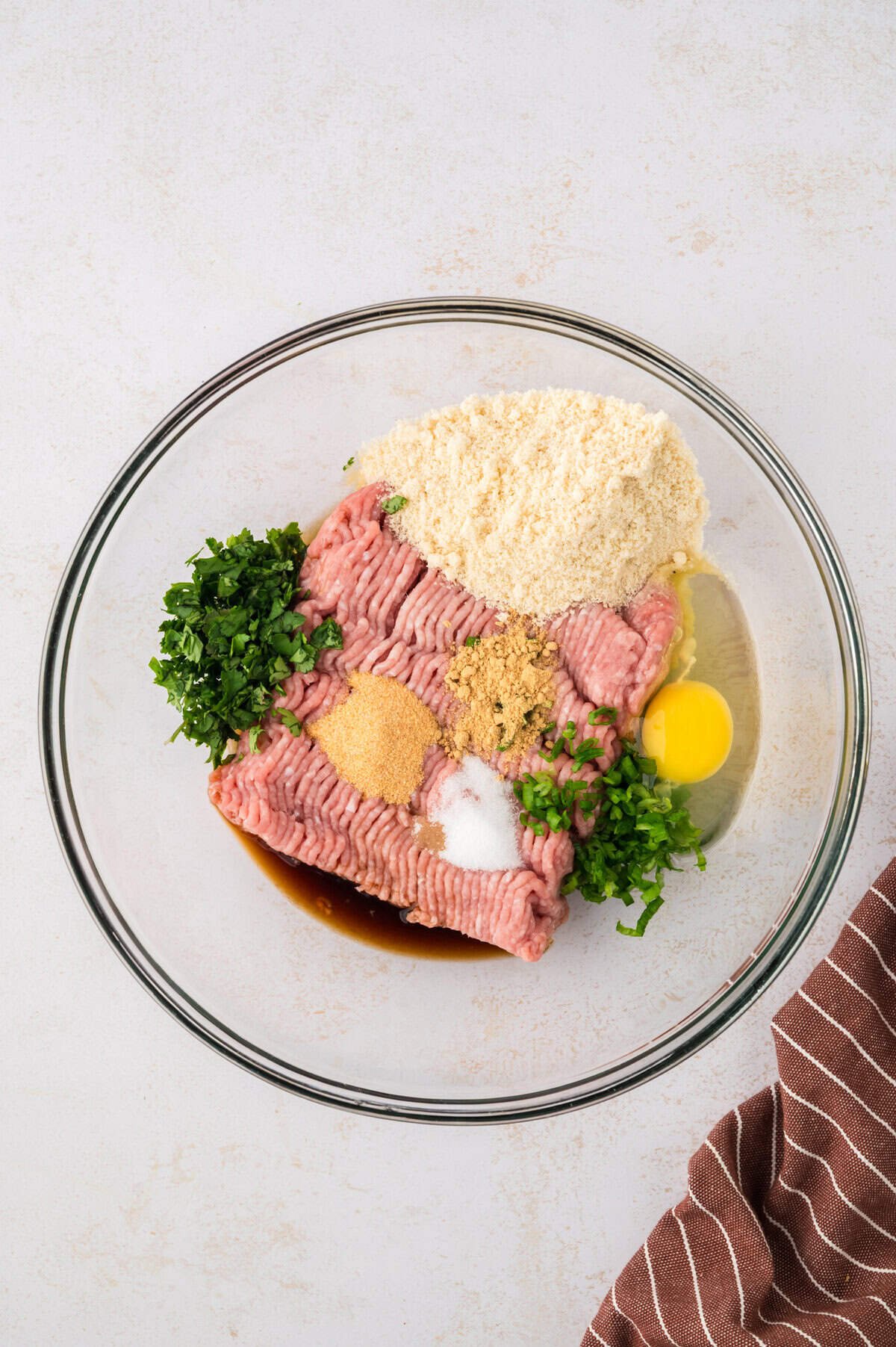 Turkey meatball ingredinets in glass mixing bowl.