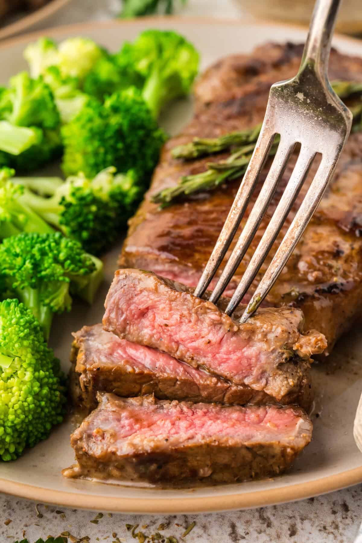 Sliced steak on plate with broccoli.