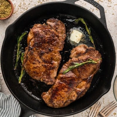 Seared steak in cast iron skillet topped with butter.