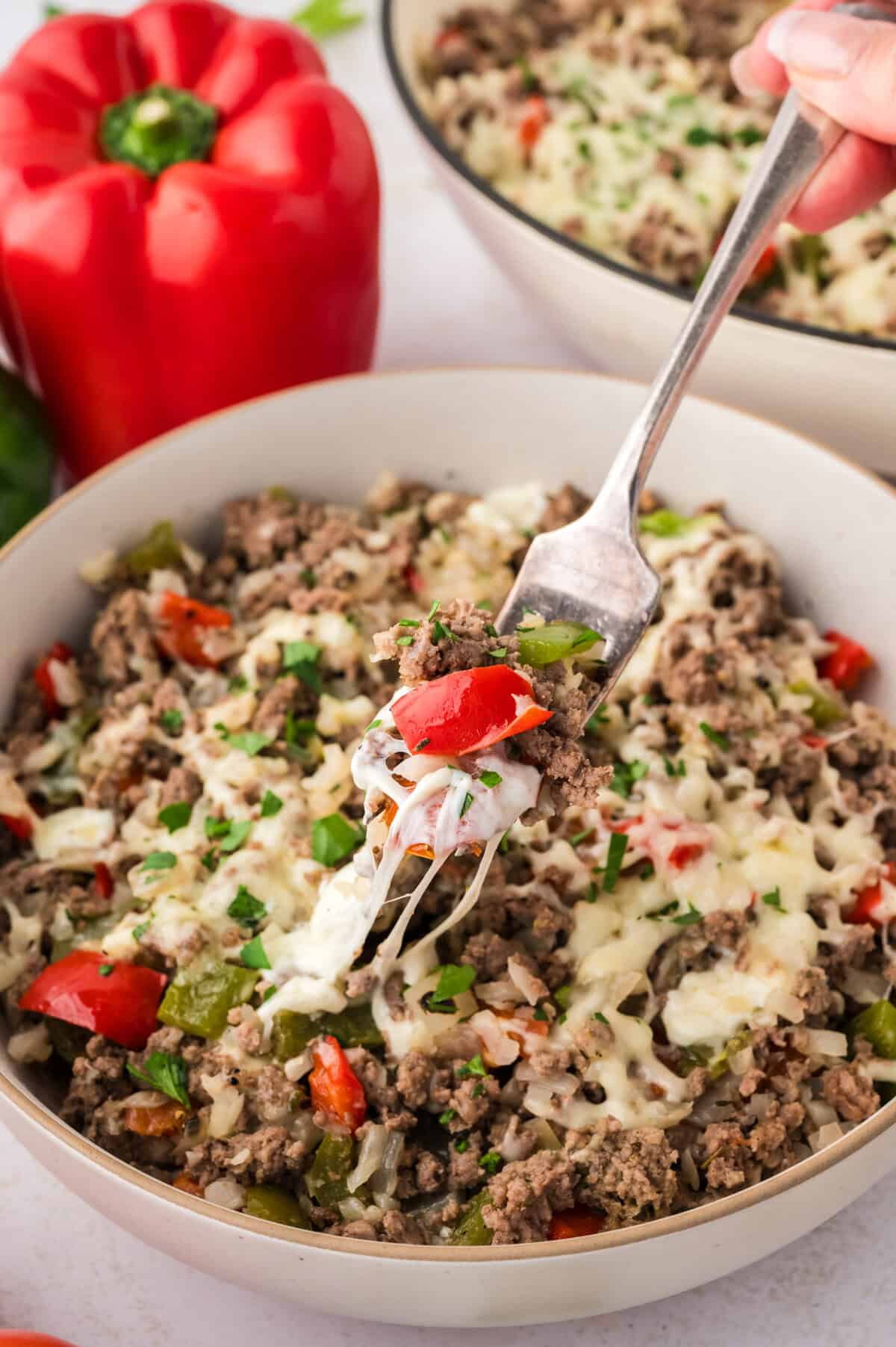 Fork full of stuffed pepper skillet in bowl.
