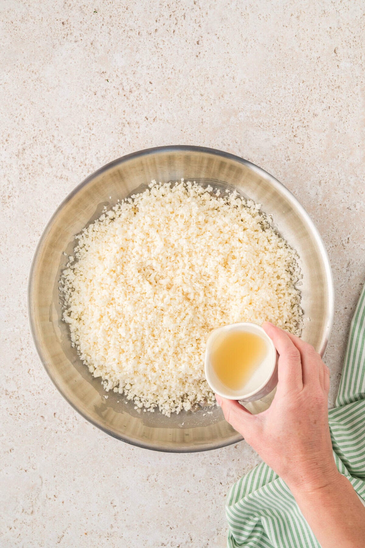 Cauliflower rice and chicken stock in skillet.