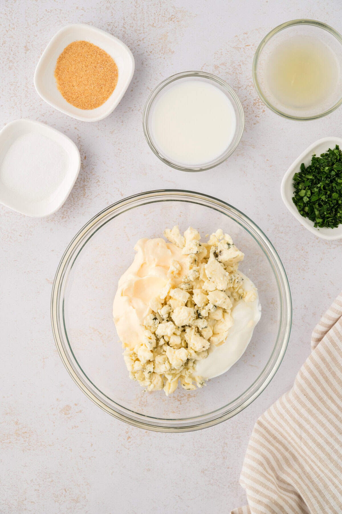 Crumbled blue cheese in bowl with mayo and sour cream.