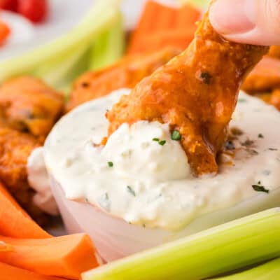 Buffalo wing being dunked in keto blue cheese dressing.
