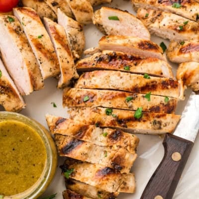 Sliced grilled chicken breast on cutting board.