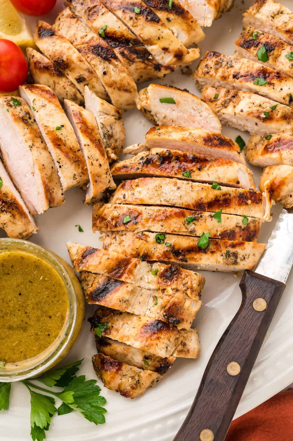 Sliced grilled chicken breast on cutting board.