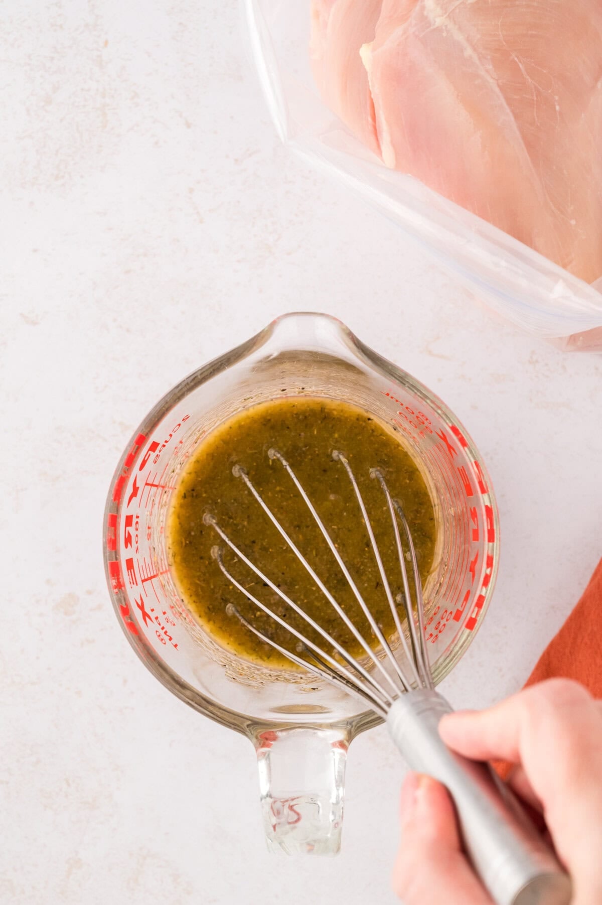 Ingredients for grilled chicken marinade being whisked together in measuring cup.