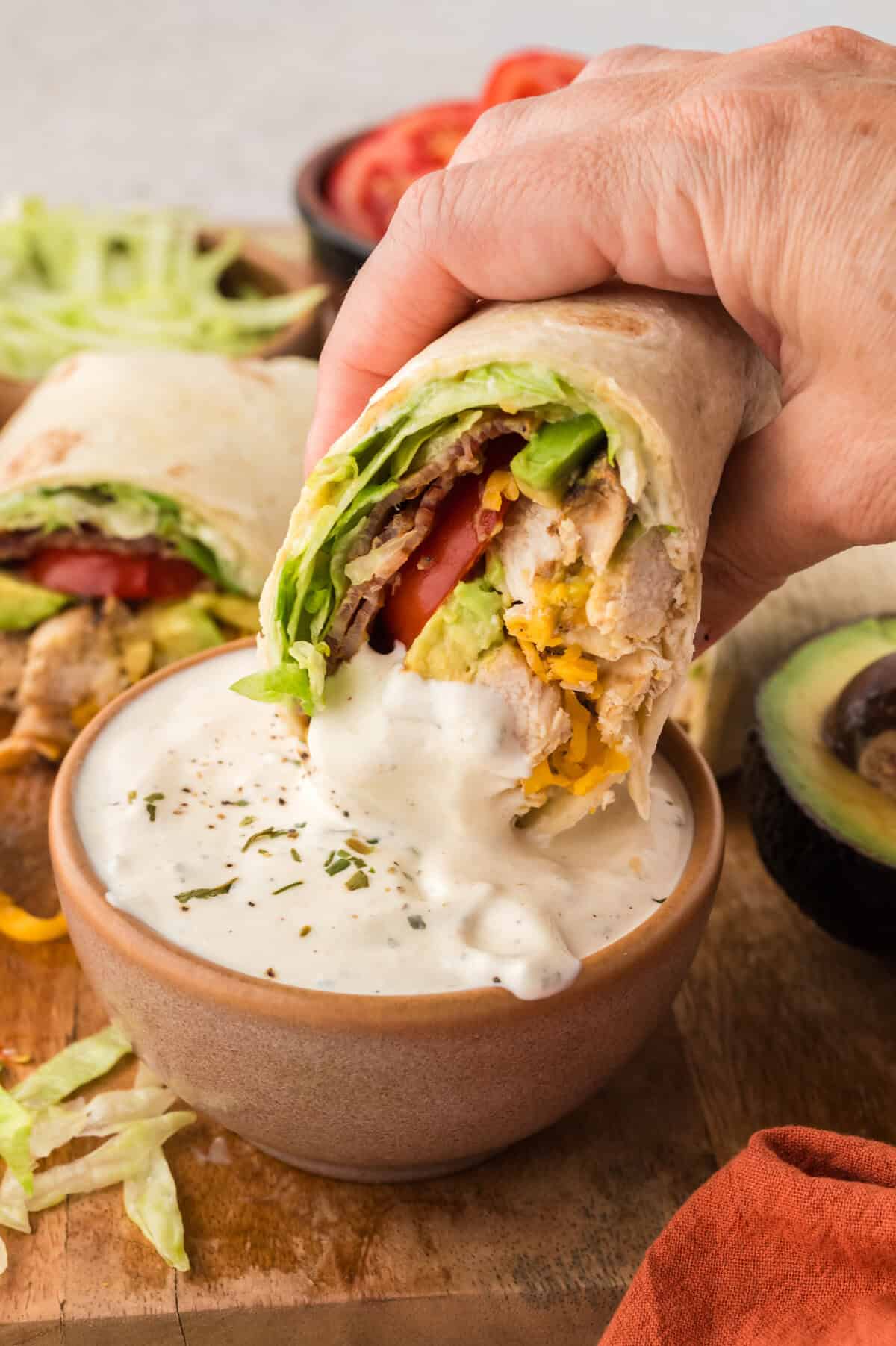 Low carb chicken club wrap being dipped in ranch dressing.