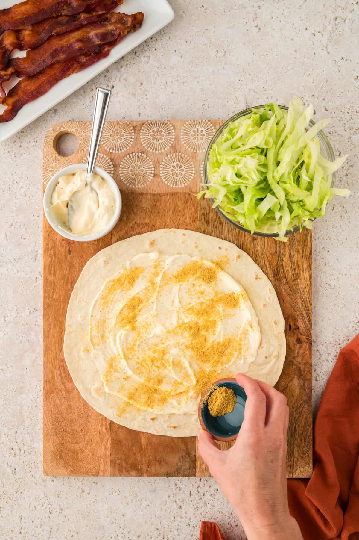 Tortilla spread with mayo and sprinkled with seasoning.