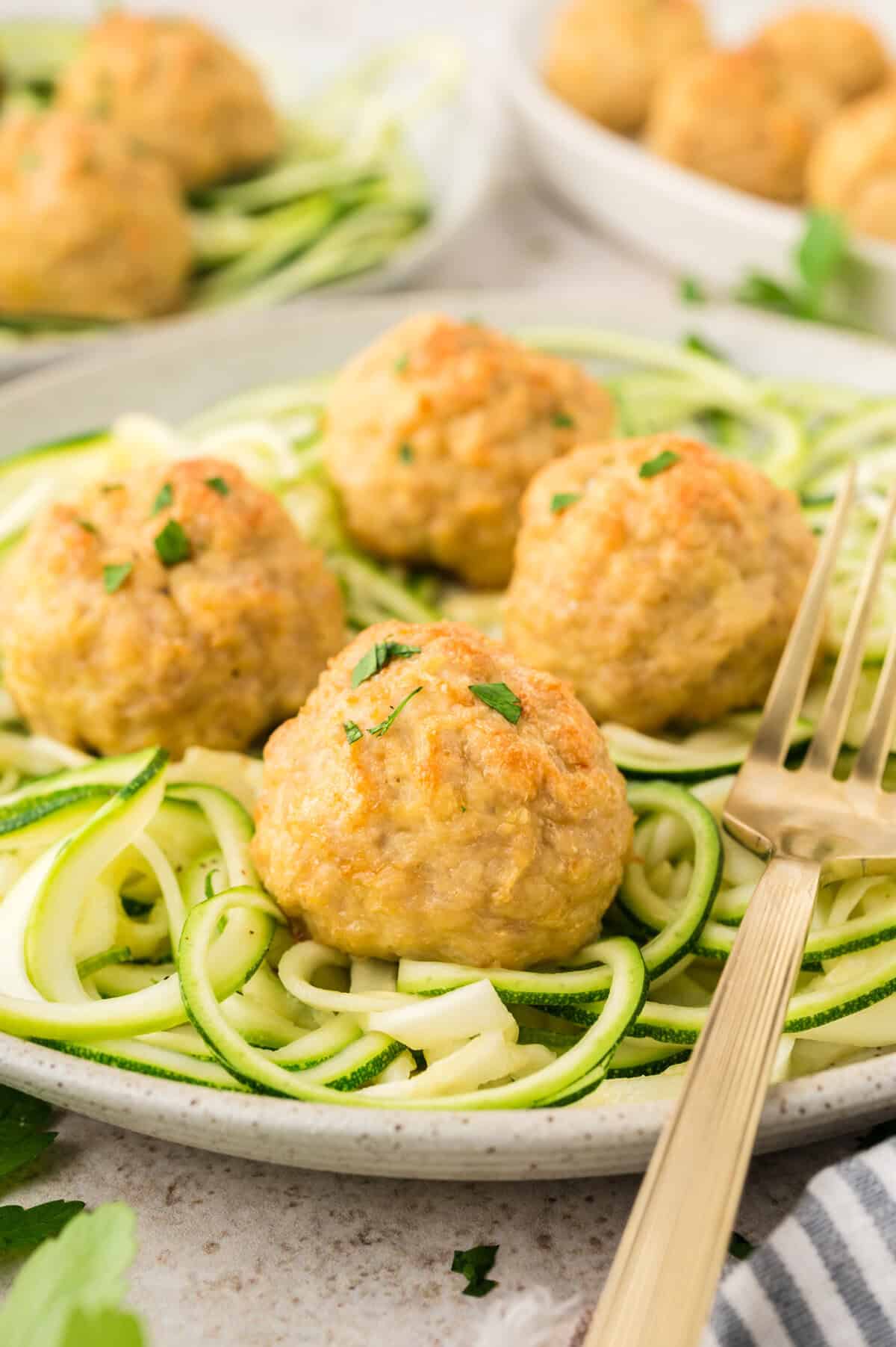 Baked keto chicken meatballs on pile of zoodles.