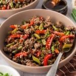 Bowl full of ground beef and vegetables with a fork.