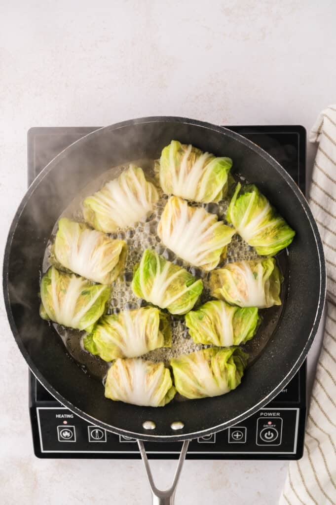 Cabbage dumplings cooking in skillet.