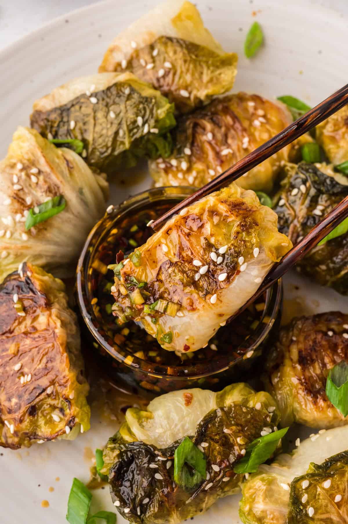 Cabbage dumpling being dunked in dipping sauce.