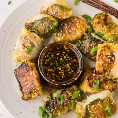 Cabbage dumplings surrounding a small dish of dipping sauce.