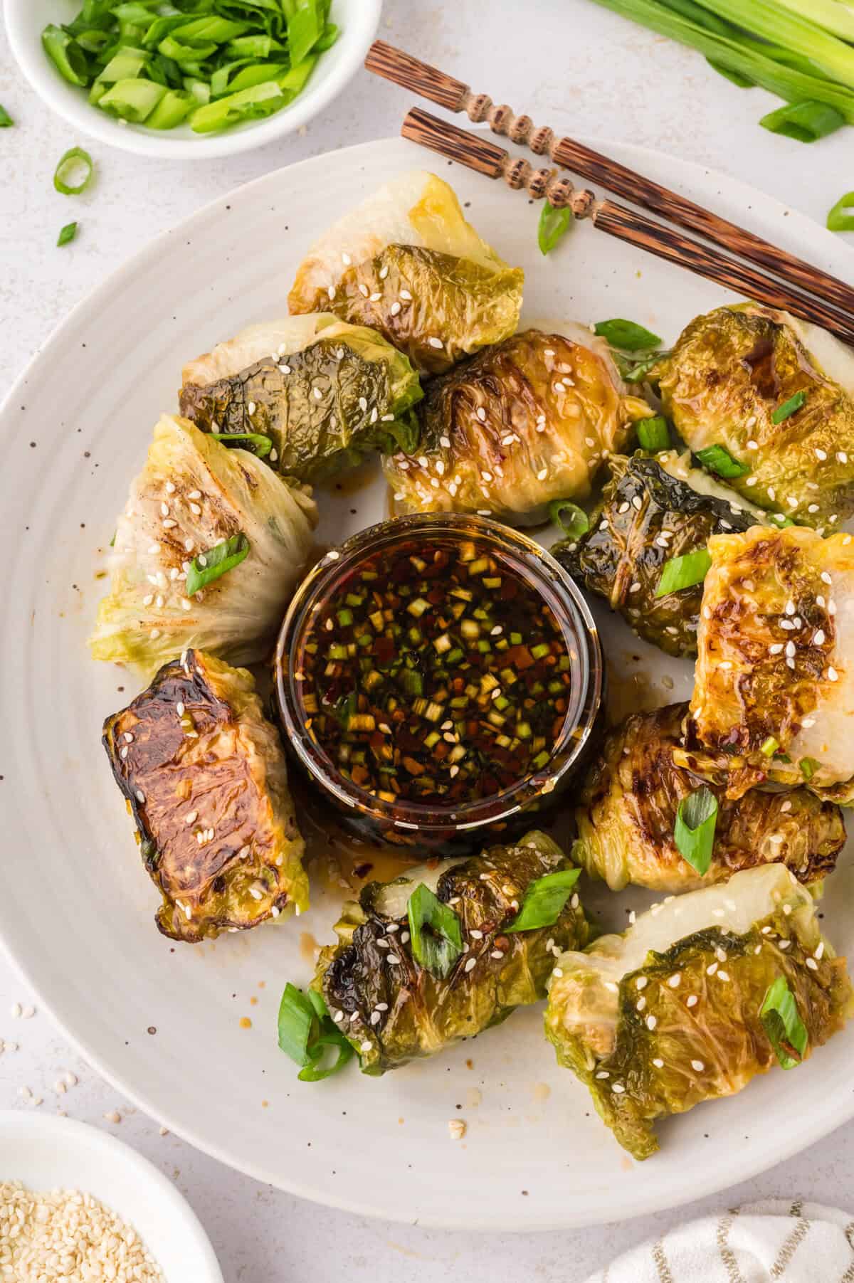 Cabbage dumplings surrounding a small dish of dipping sauce.