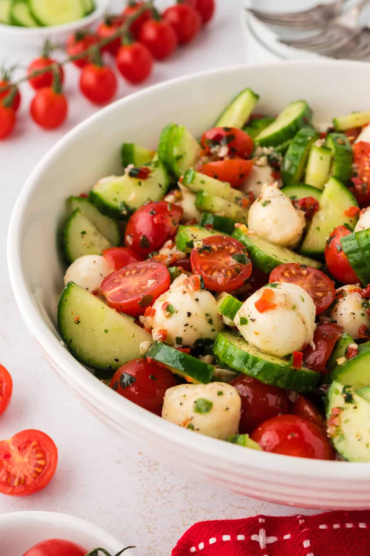 Tomato cucumber mozzarella salad in white bowl.