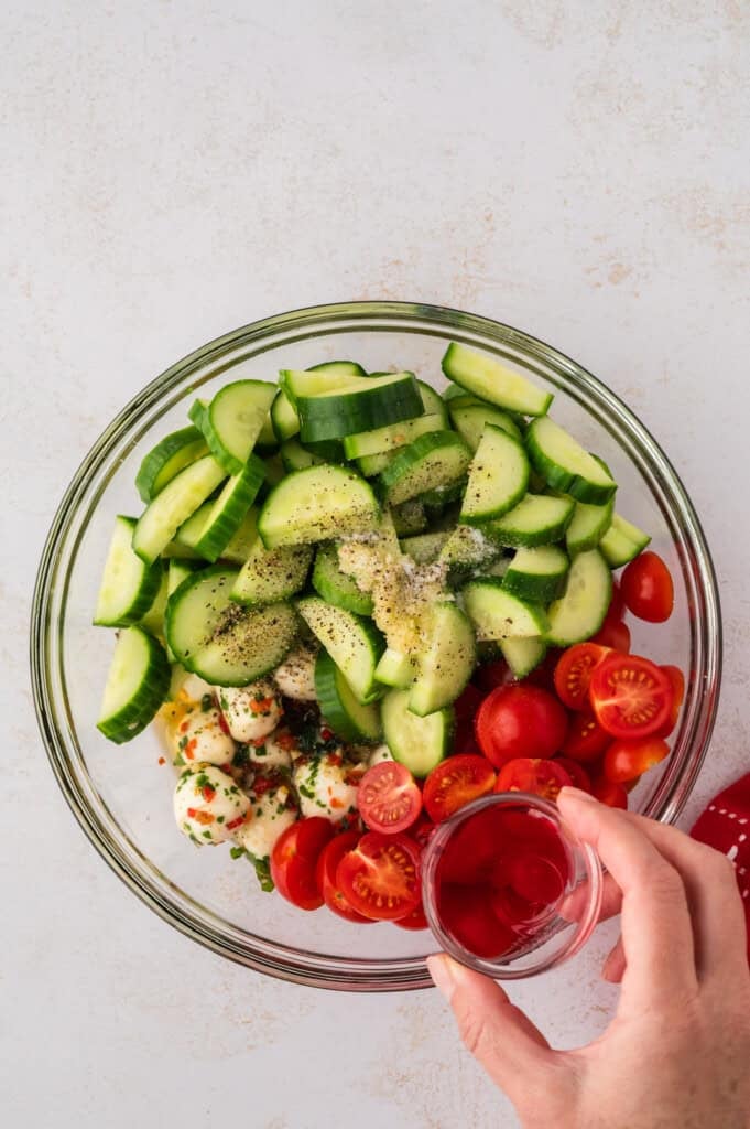 Ingredients for tomato cucumber mozzarella salad in mixing bowl.