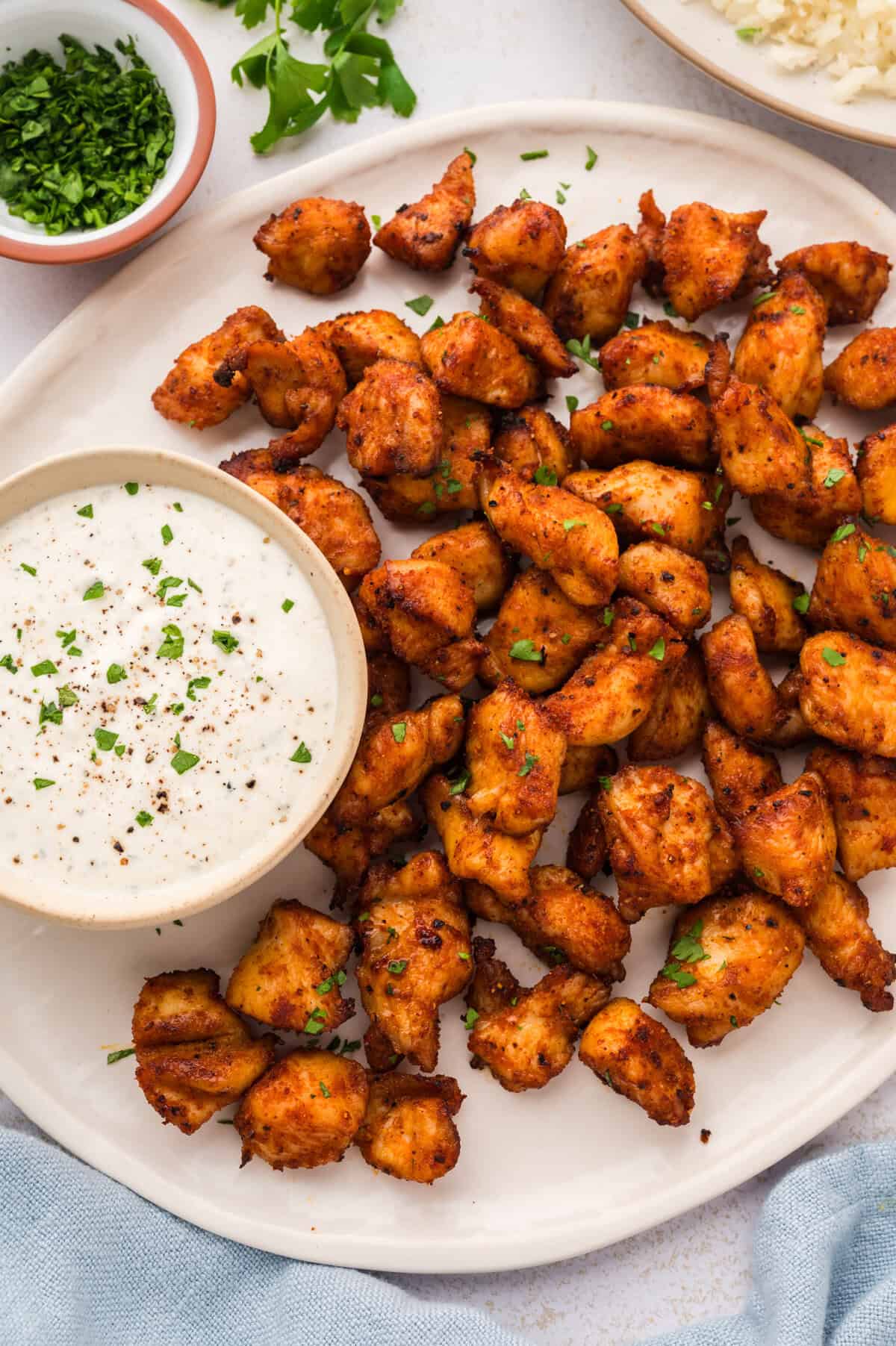 Air fryer chicken bites on plate with ranch dip.