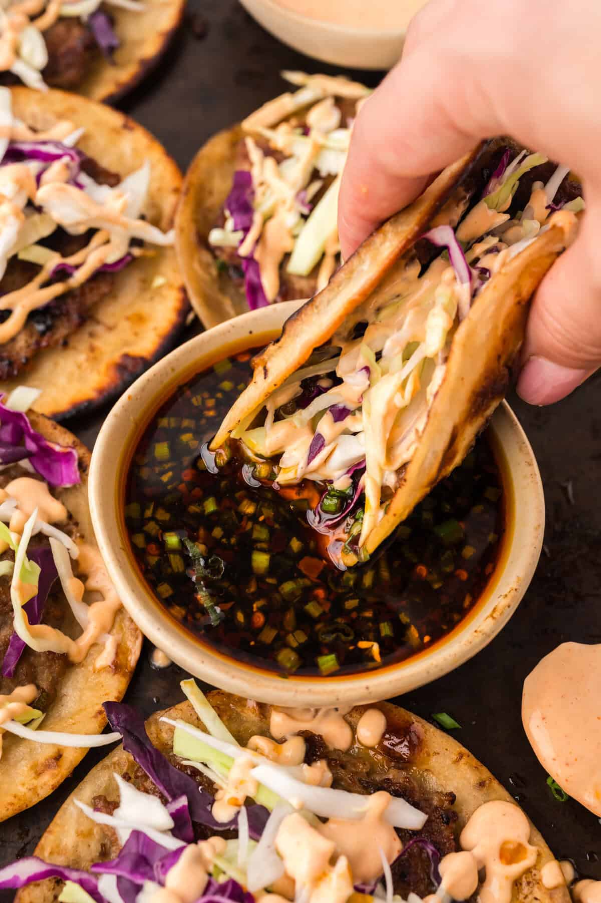Keto egg roll taco being dipped in soy sesame sauce.