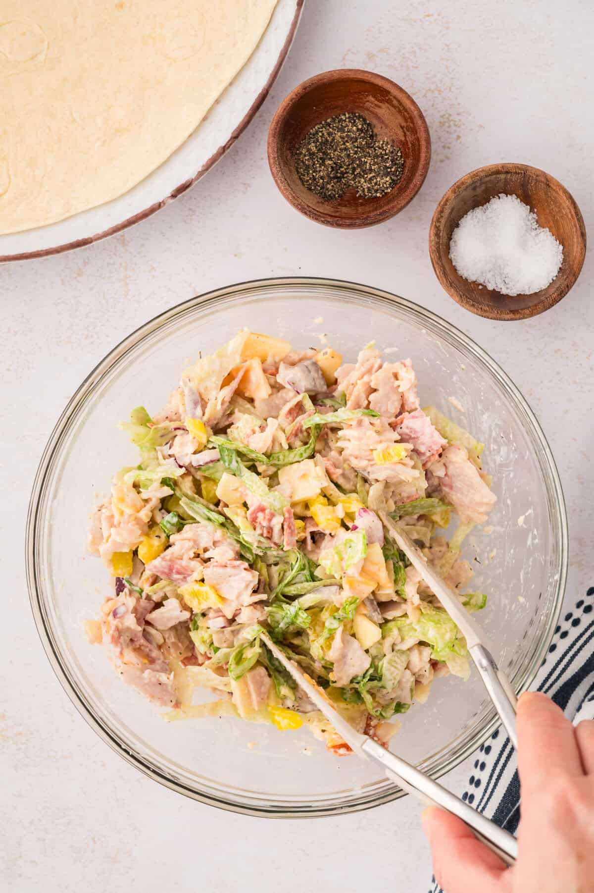 Sandwich and salad ingredients being tossed together.