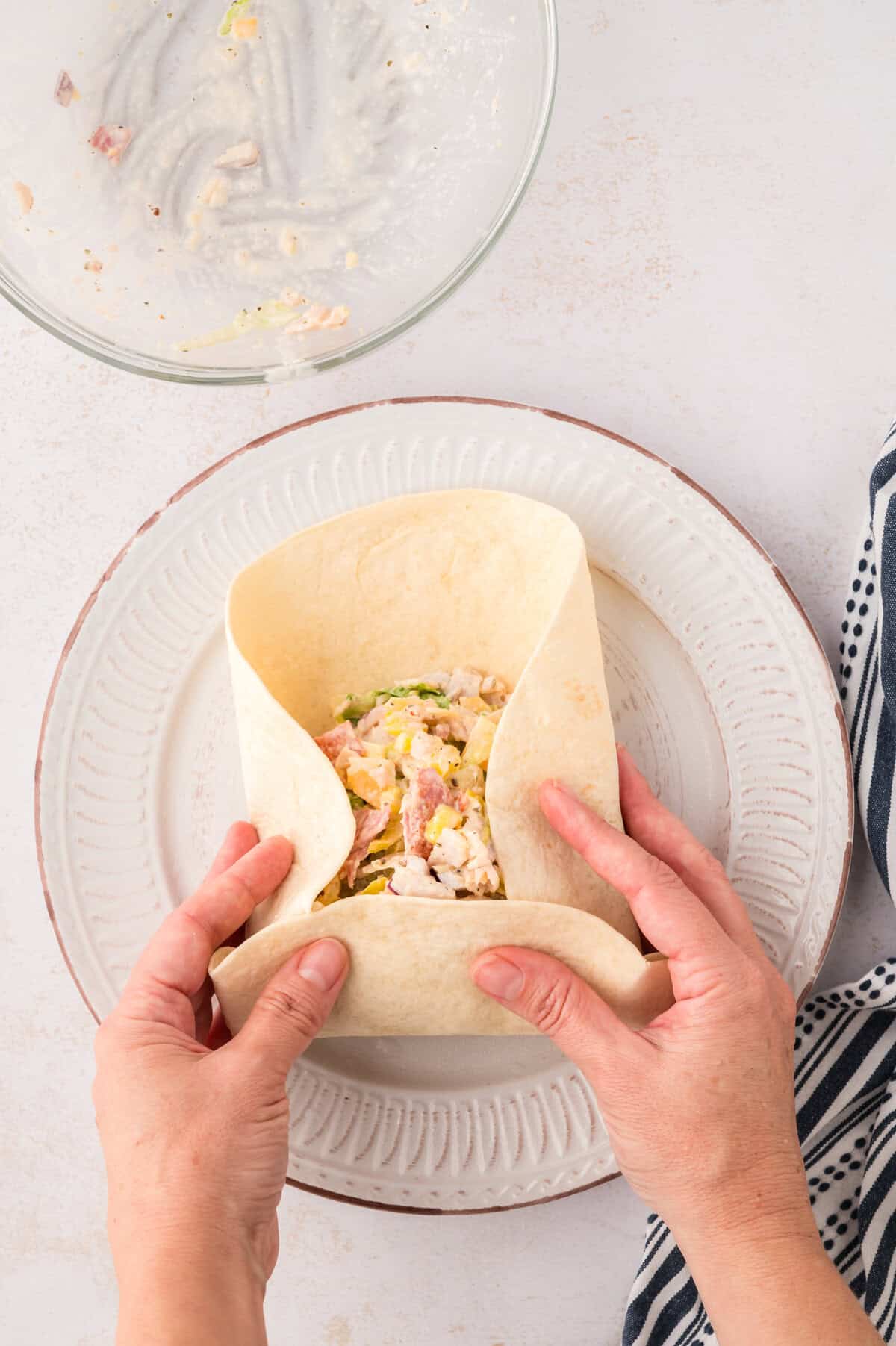 Hands folding a tortilla to make a wrap.