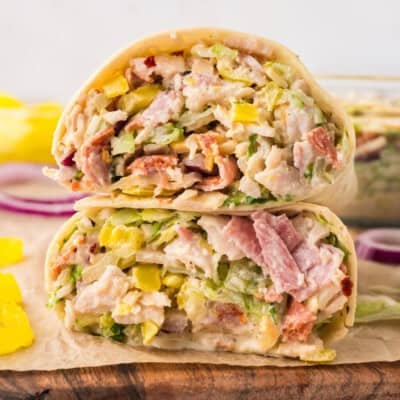 Italian grinder wrap cut in half on cutting board.