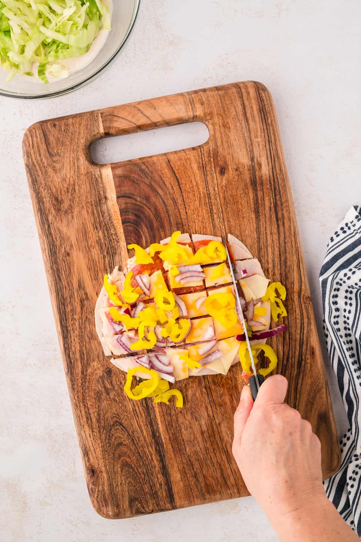 Ingredients for Italian grinder wrap being chopped together on cutting board.