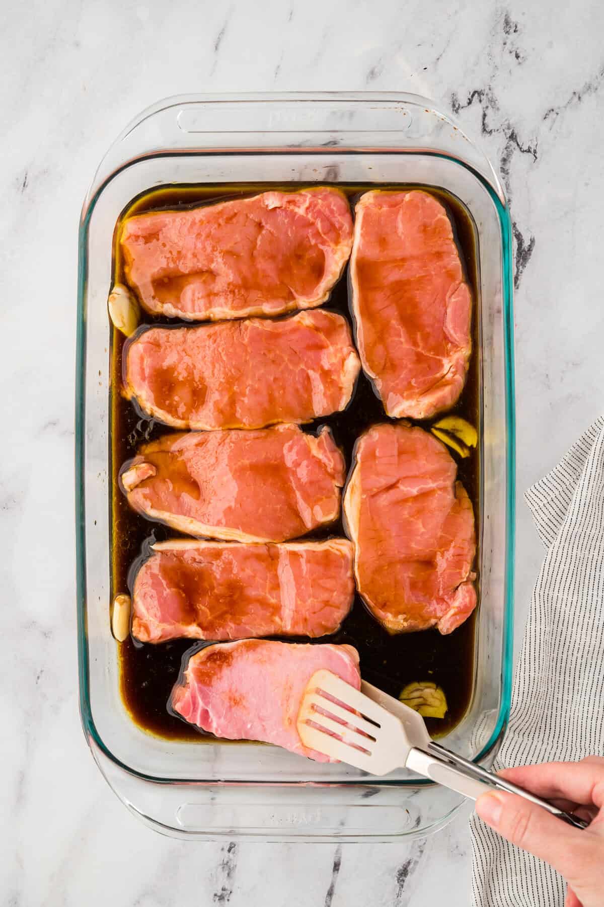 Pork chops being placed in marinade.