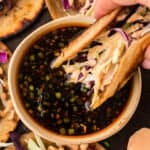 Egg roll taco being dipped in soy ginger sauce.