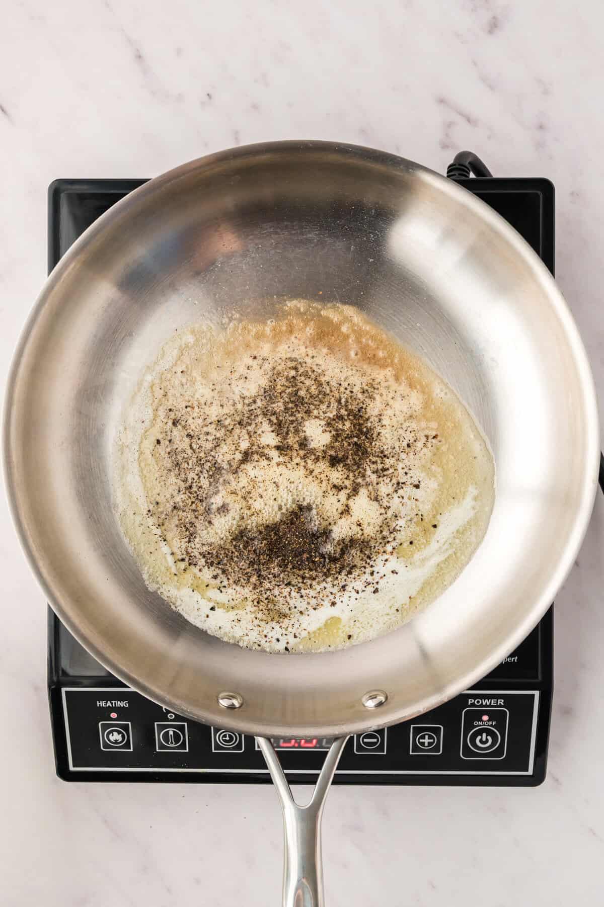 Cracked pepper being toasted in butter.