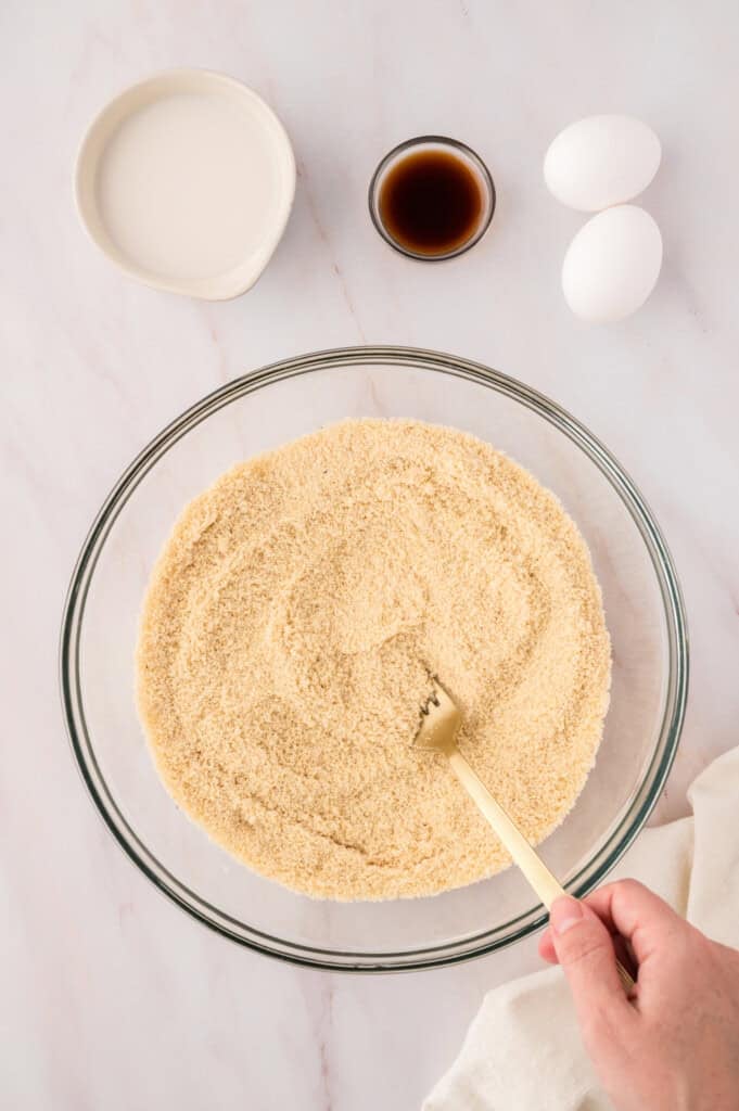 Dry ingredinets being stirred together with a fork in a mixing bowl.