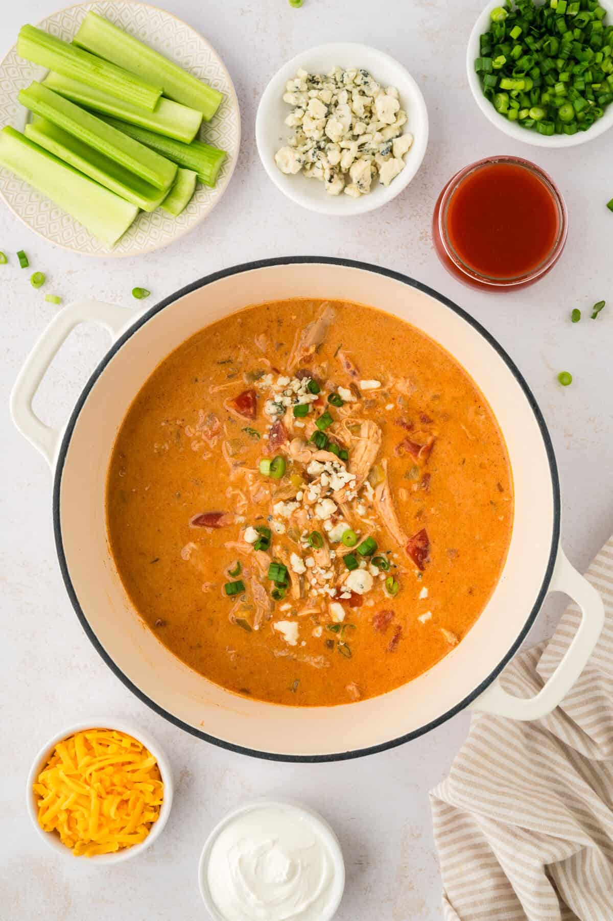 Keto buffalo chicken soup in pot topped with cheese and green onion.