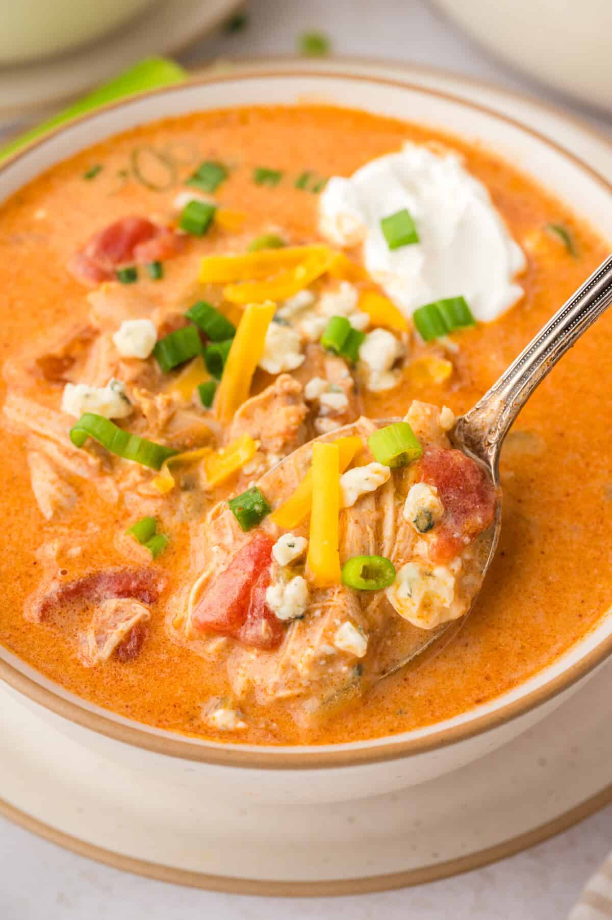 Spoonful of buffalo chicken soup over bowl.