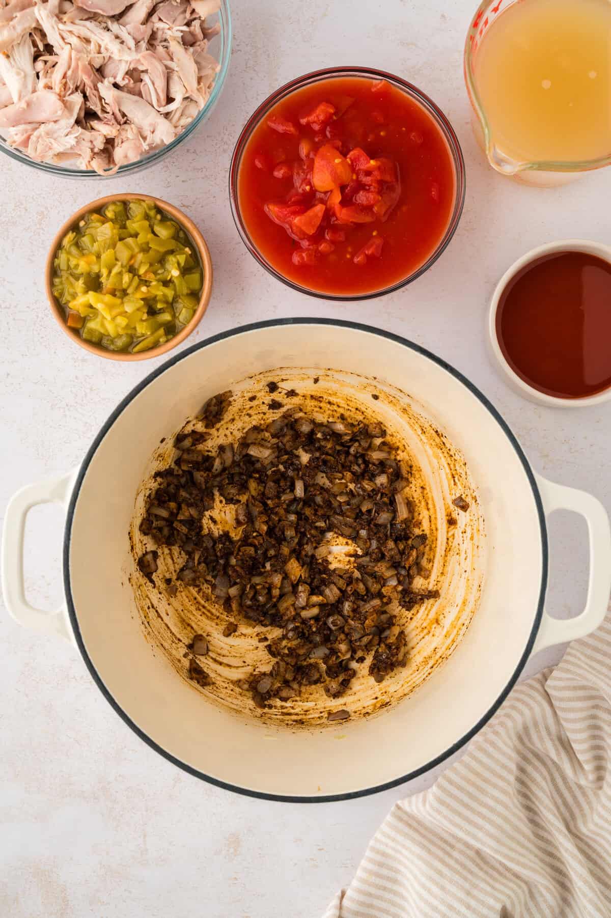 Onions coated in spices being cooked in dutch oven.