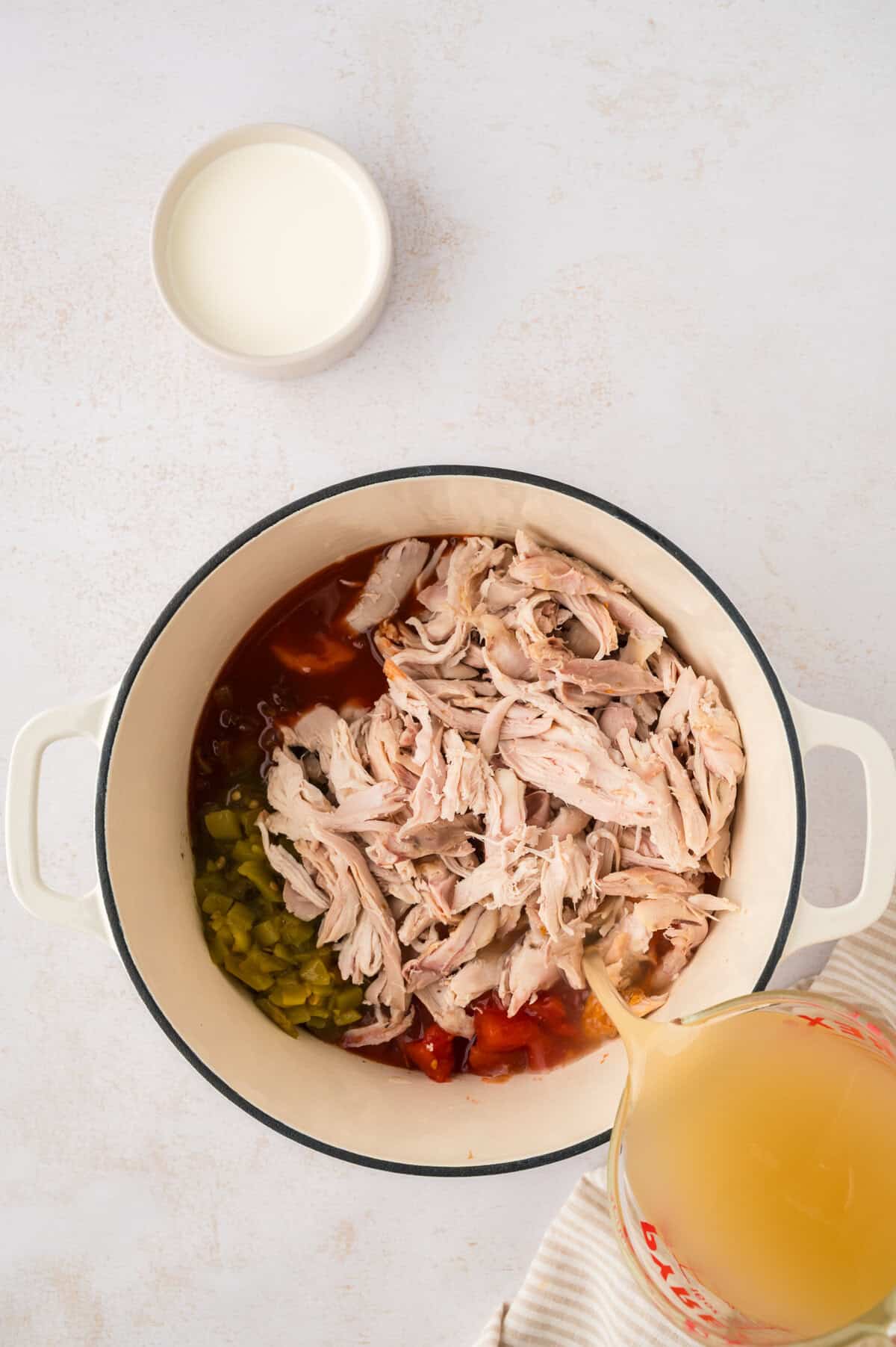Shredded chicken, tomatoes, and broth in dutch oven.