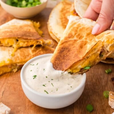 Chicken bacon ranch quesadilla being dipped into ranch dressing.