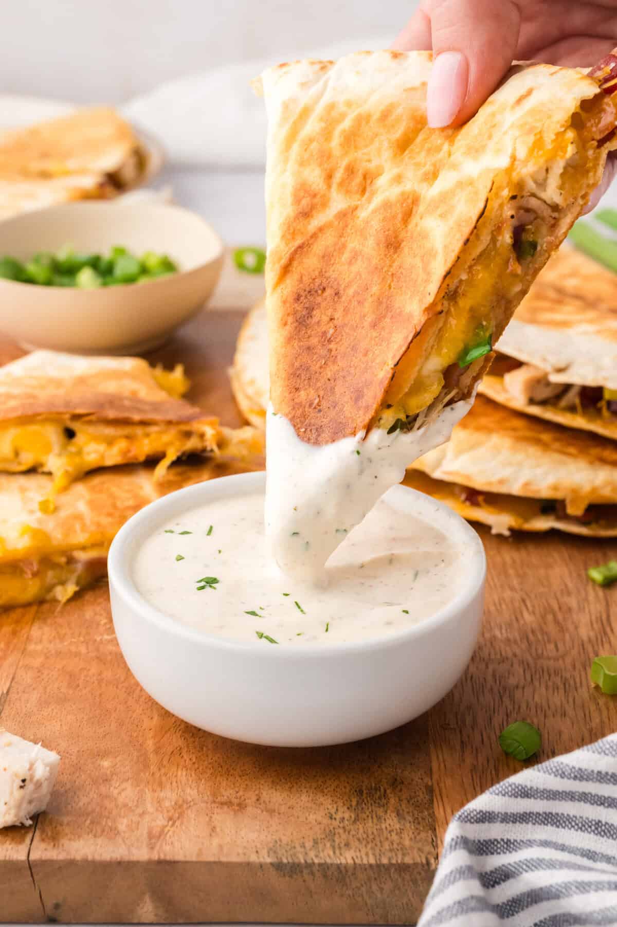 Chicken bacon ranch quesadilla being dipped into ranch dressing.