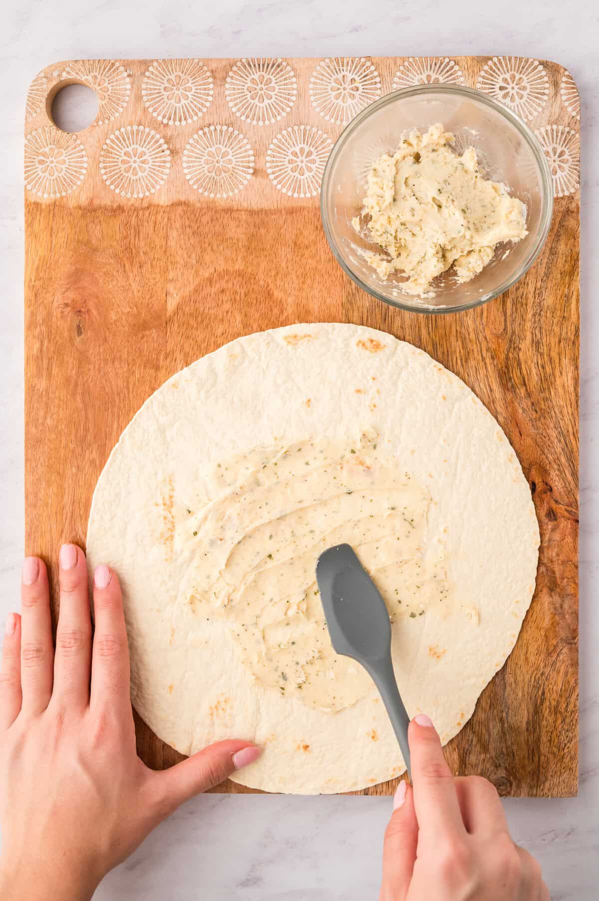 Cream cheese being spread on quesadilla.