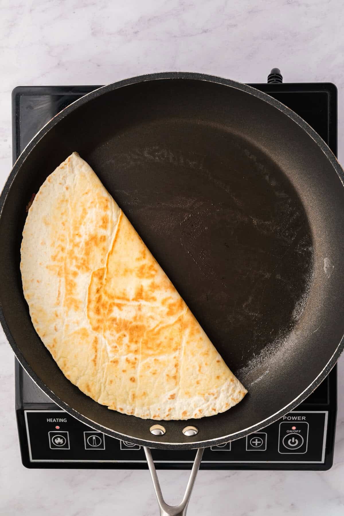Cooked quesadilla on skillet.