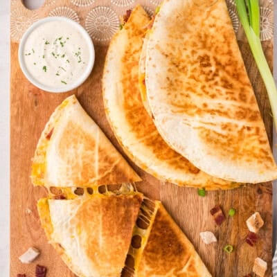 Sliced chicken bacon ranch quesadillas on cutting board.