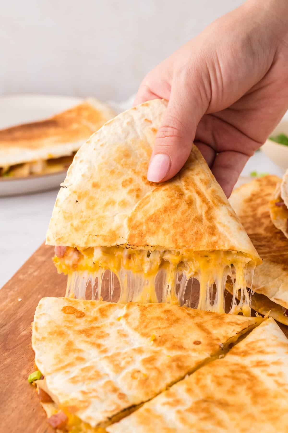 Cheesy chicken bacon ranch quesadilla on a cutting board.