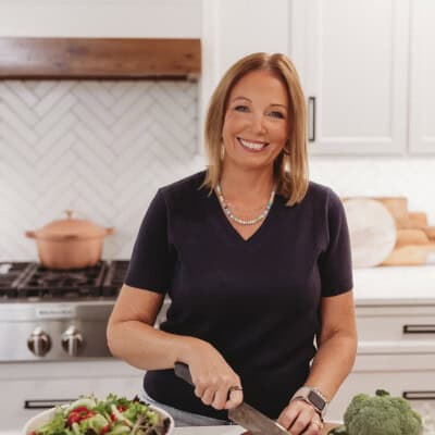 Karly Campbell, of thatlowcarblife.com, standing in her home kitchen cutting vegetables.