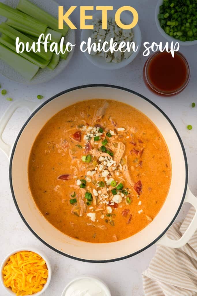 Dutch oven full of buffalo chicken soup, topped with cheese and green onion.